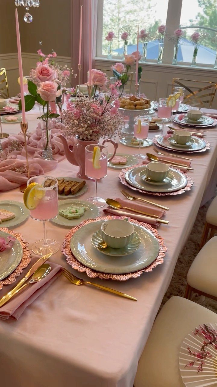 Pink themed tea party table setting with green plates, gold cutlery, and roses.