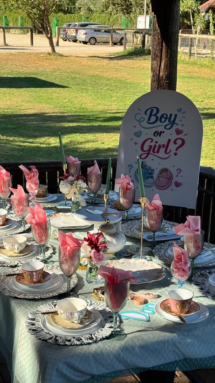 Tea party table setting with a Boy or Girl gender reveal sign outdoors.