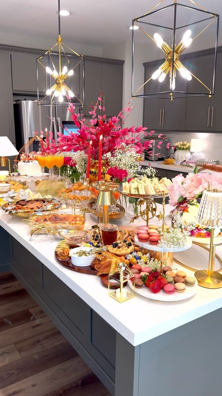 Lavish dessert spread with macarons and pink flowers on a white kitchen island