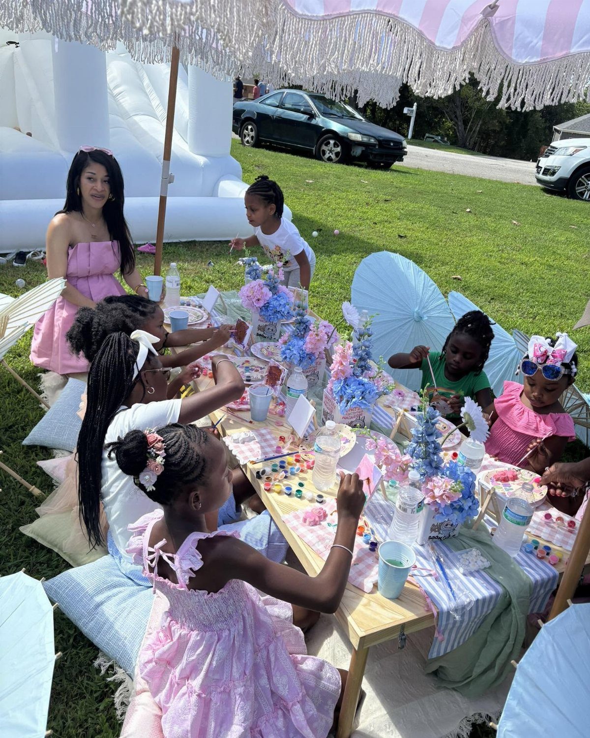 Young girls enjoying a playful tea party with floral decorations outdoors under a canopy