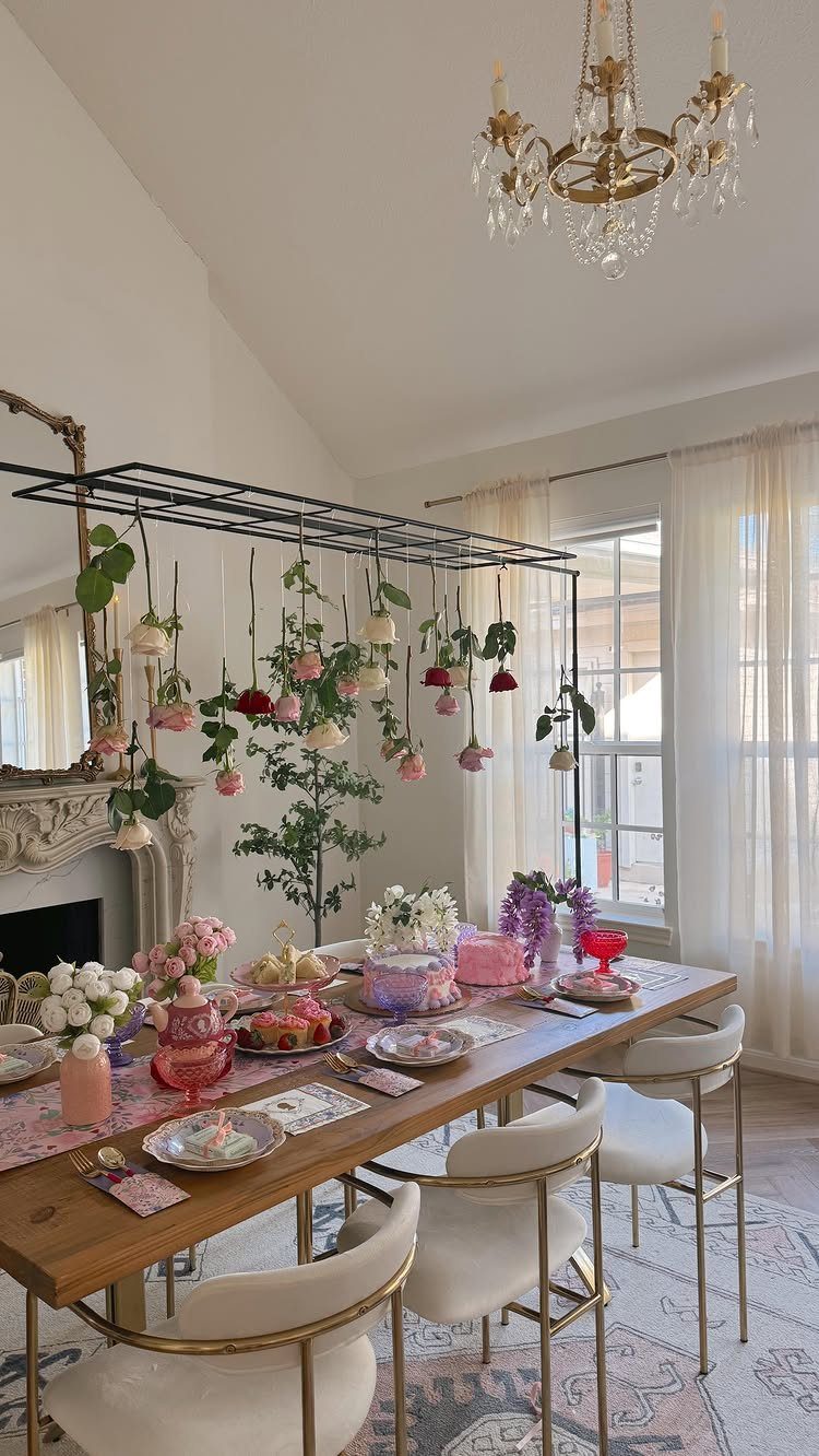 Tea party table with pink desserts and roses hanging from a metal frame.
