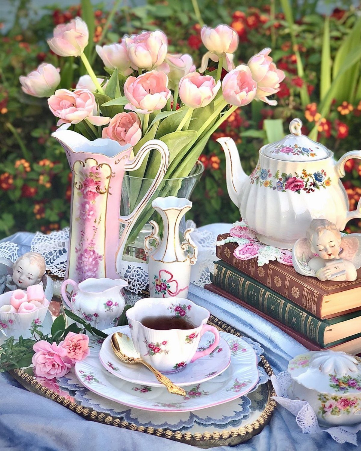 Vintage floral tea set with pink tulips and old books in a garden