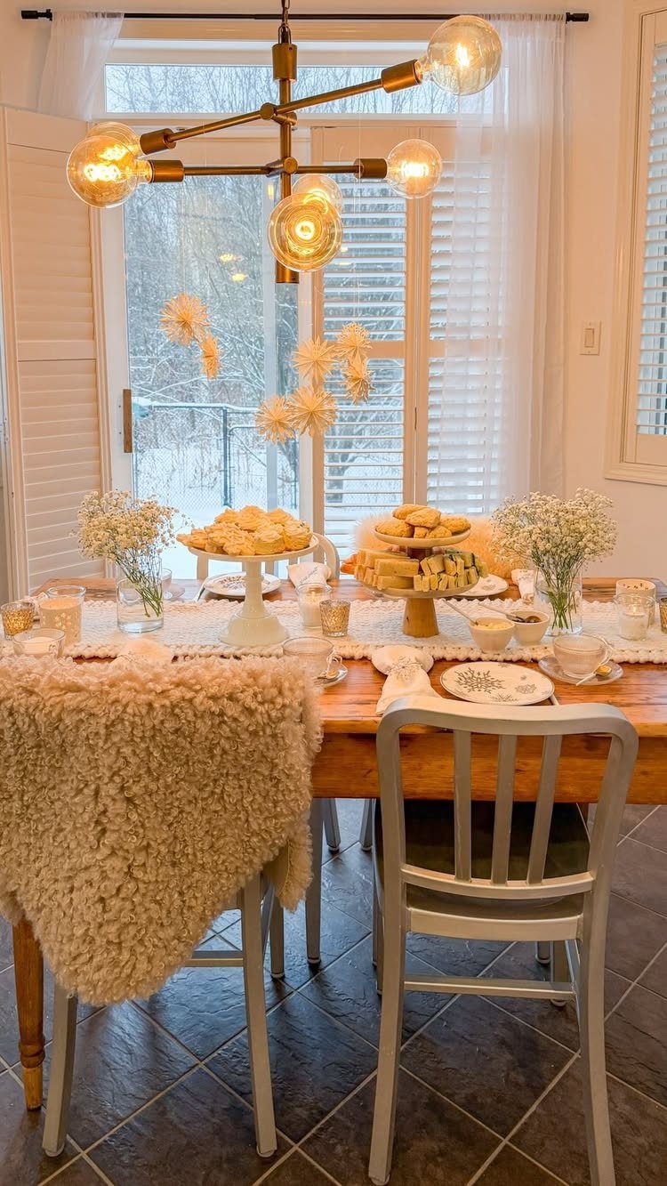 Tea party table setting with pastries and flowers, snowy winter landscape in background