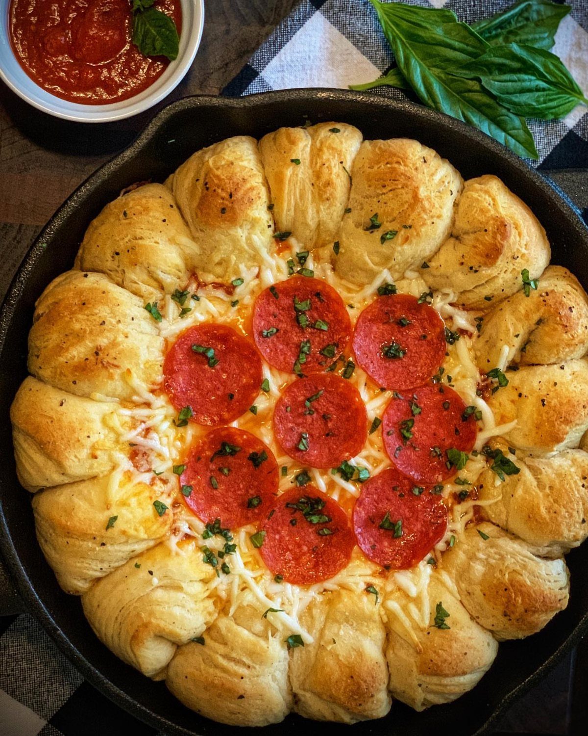 Pepperoni and cheese pull apart bread in a cast iron skillet with marinara sauce.