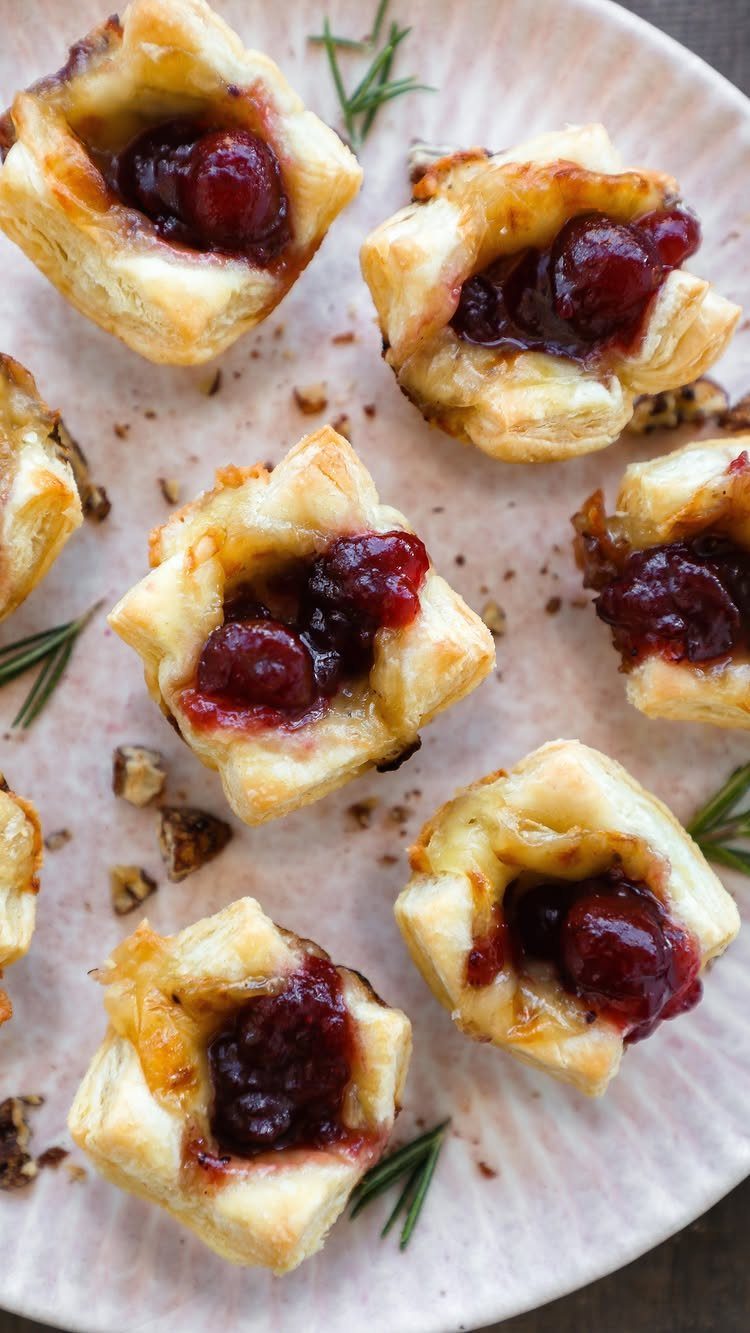 Puff pastry bites filled with melted cheese and topped with red cranberry jam.