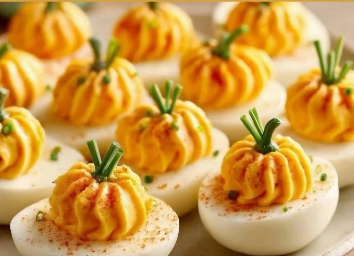 Deviled eggs with yolk filling piped into pumpkin shapes topped with chive stems.
