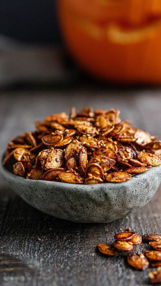 Roasted seasoned pumpkin seeds in a grey stone bowl on a wooden table