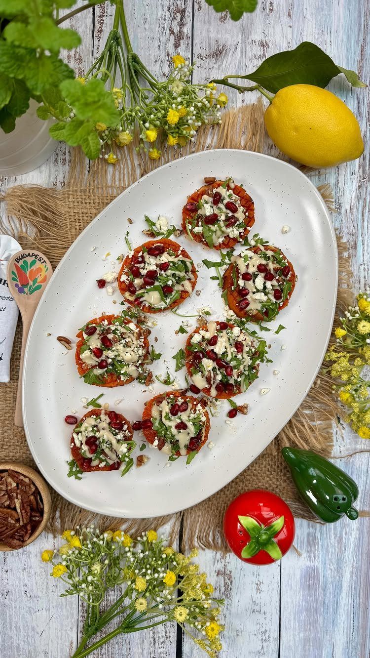 Roasted sweet potato rounds topped with white cheese, pomegranate seeds, and fresh herbs.