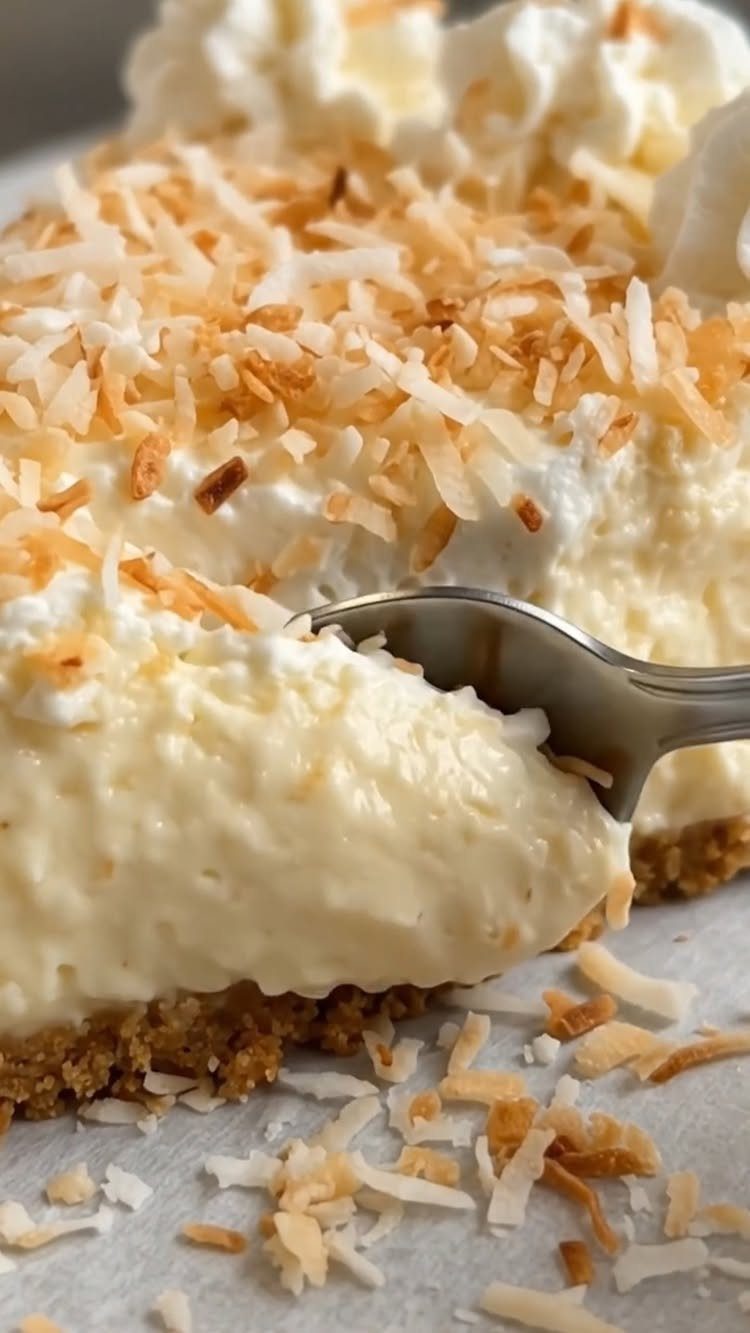 Coconut cream pie slice with toasted coconut flakes and a metal fork.