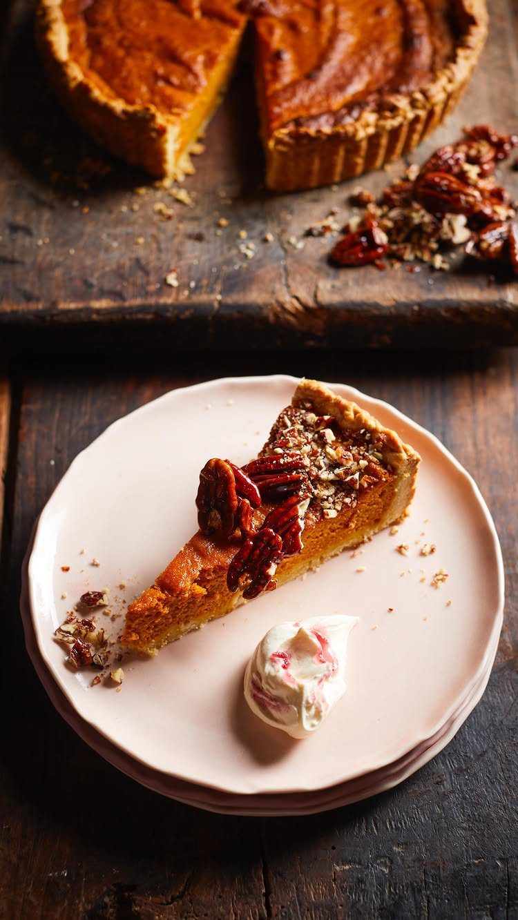 Slice of pumpkin pie with pecans and whipped cream on a pink plate
