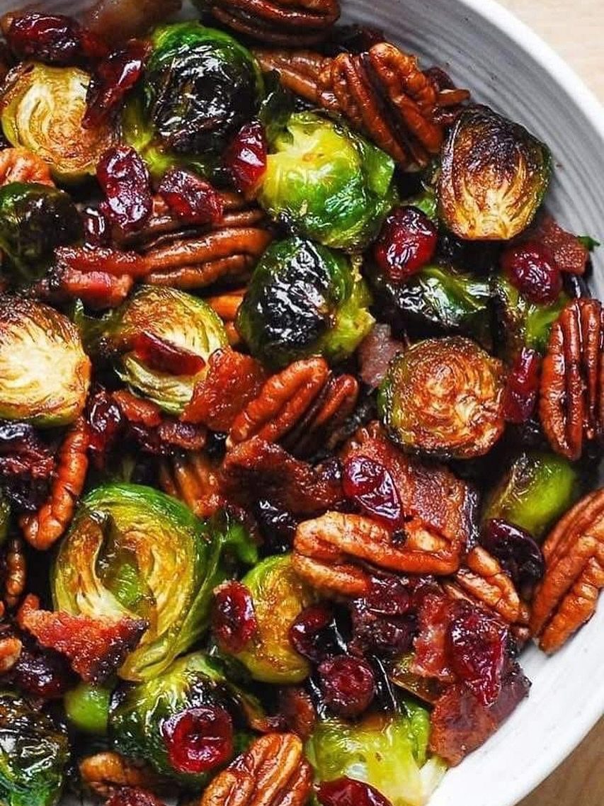 Roasted Brussels sprouts with pecans, dried cranberries, and bacon in a white bowl.