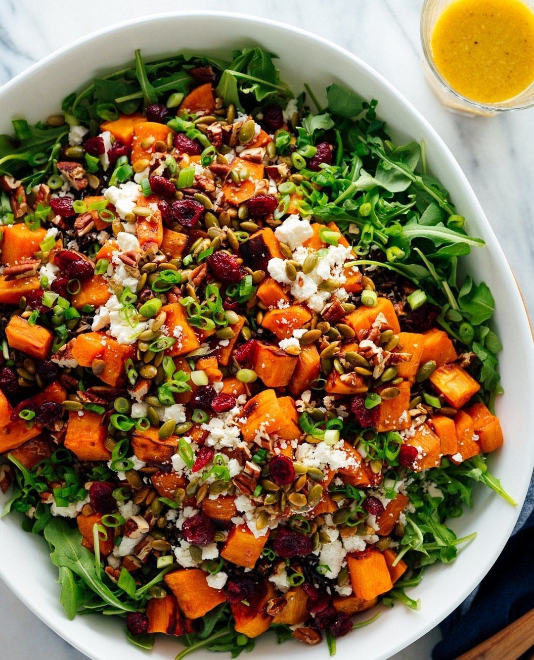 Roasted butternut squash salad with cranberries, seeds, and feta on arugula leaves