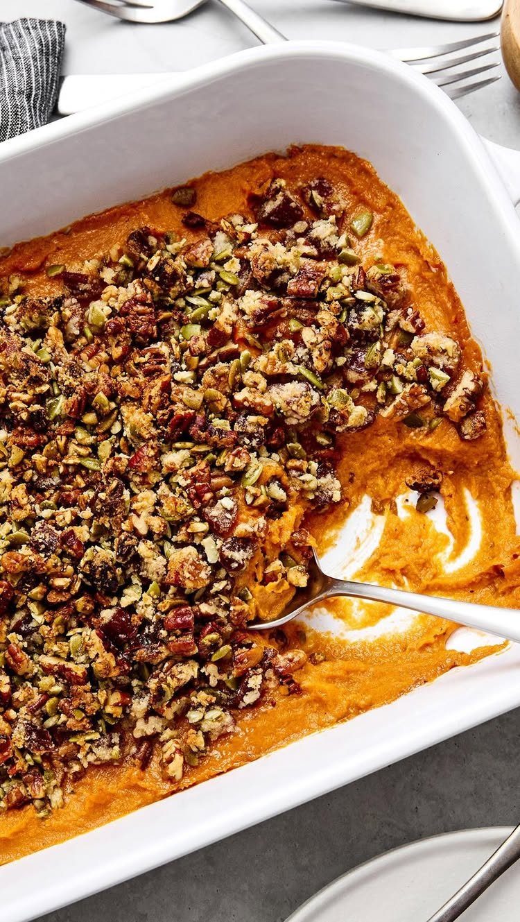 Sweet potato casserole with a nut crumble topping in a white baking dish