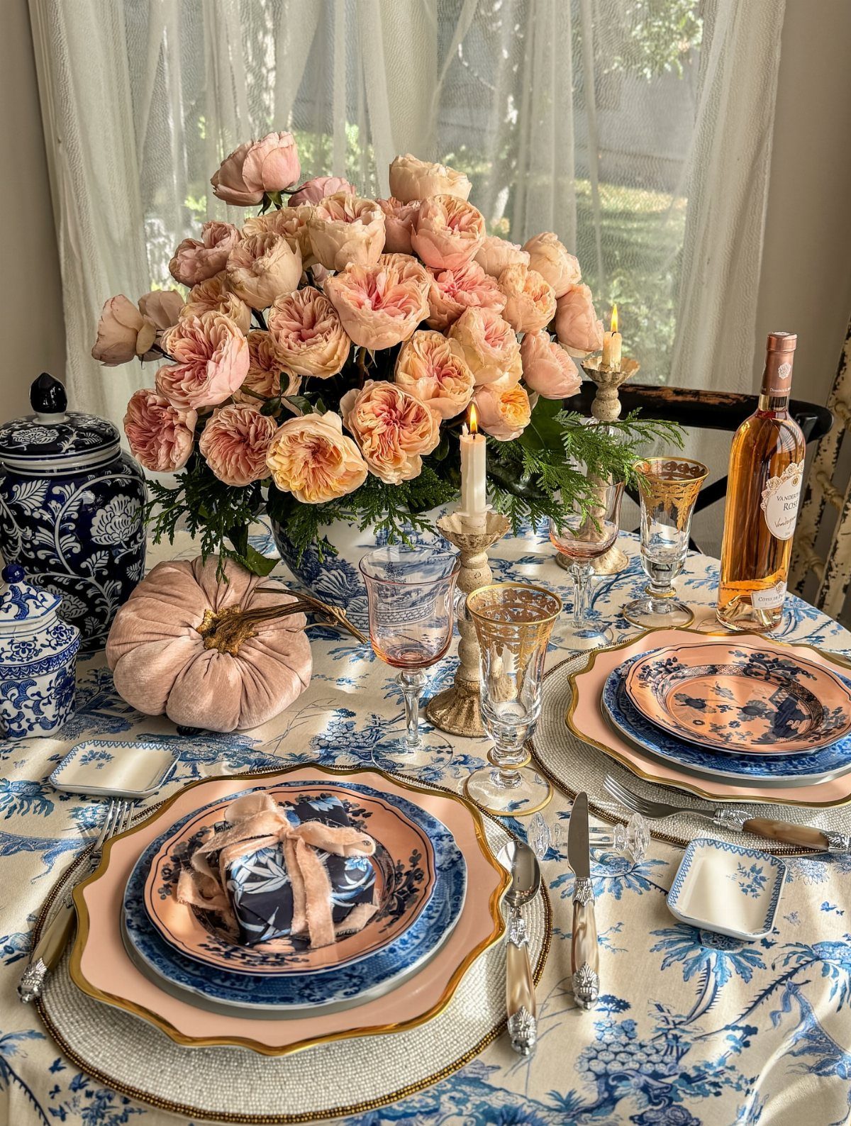Elegant table setting with blue and white floral linens, peach roses, and china.