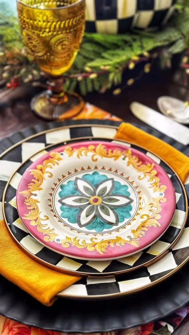 Gold textured glass goblet next to a colorful layered plate setting with yellow napkin.