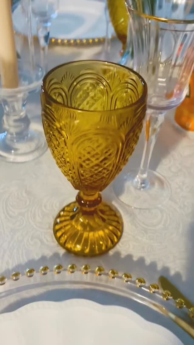 Amber pressed glass goblet and clear crystal glassware on a white damask tablecloth