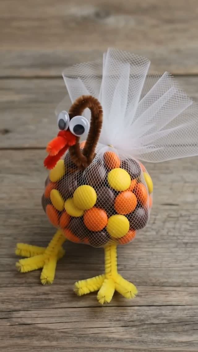 Turkey-shaped candy treat with pipe cleaner legs and white tulle tail on wood.