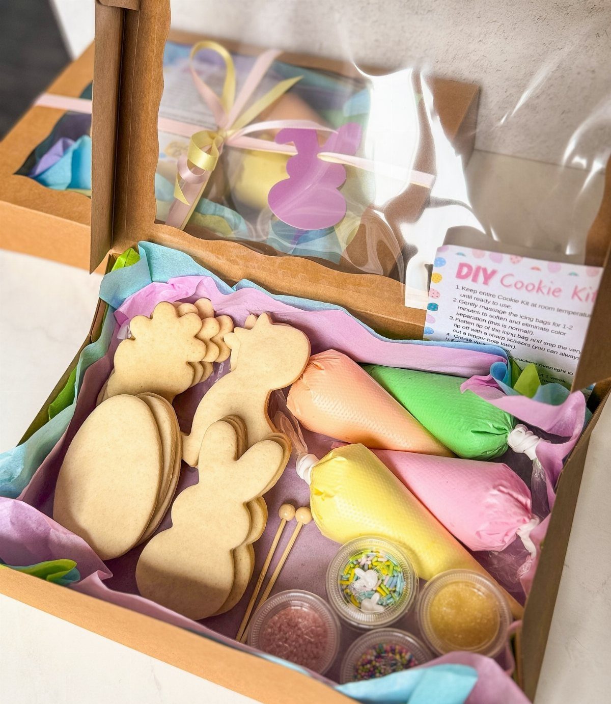 Bunny-shaped cookies and colorful frosting piping bags in a DIY cookie kit box.