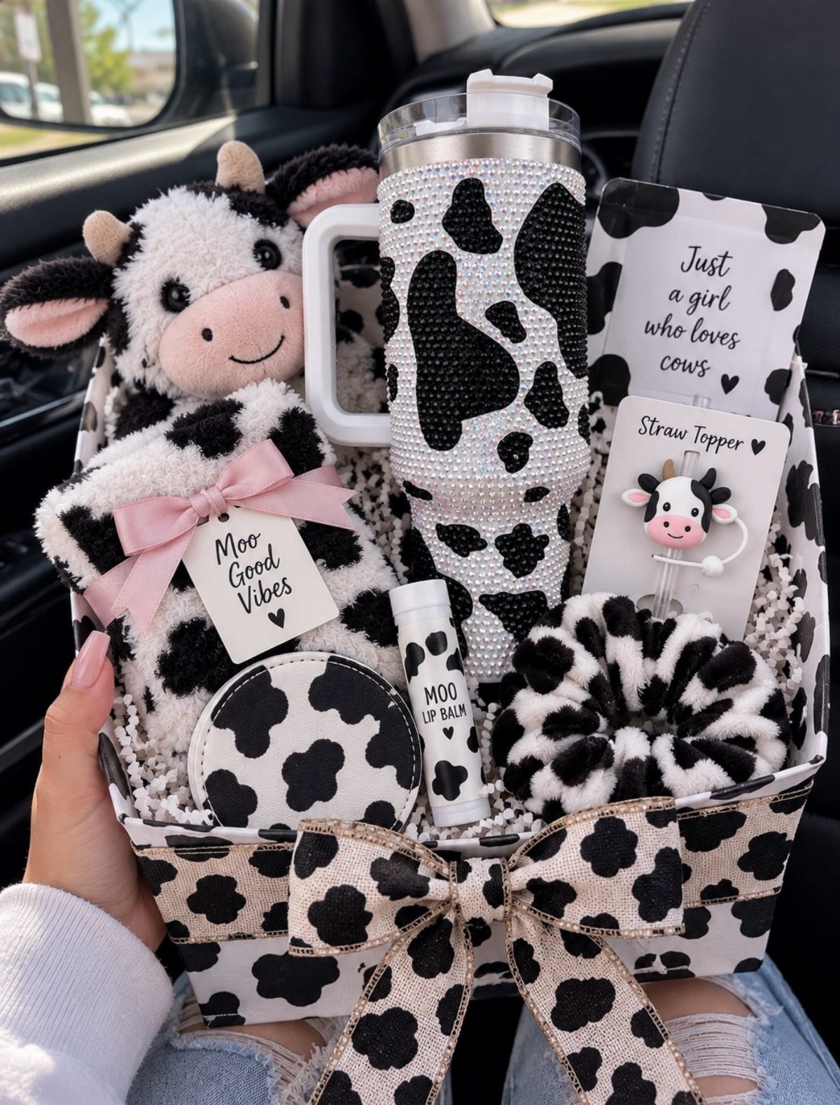 Cow-themed gift basket with plush toy, tumbler, and accessories in black and white patterns.