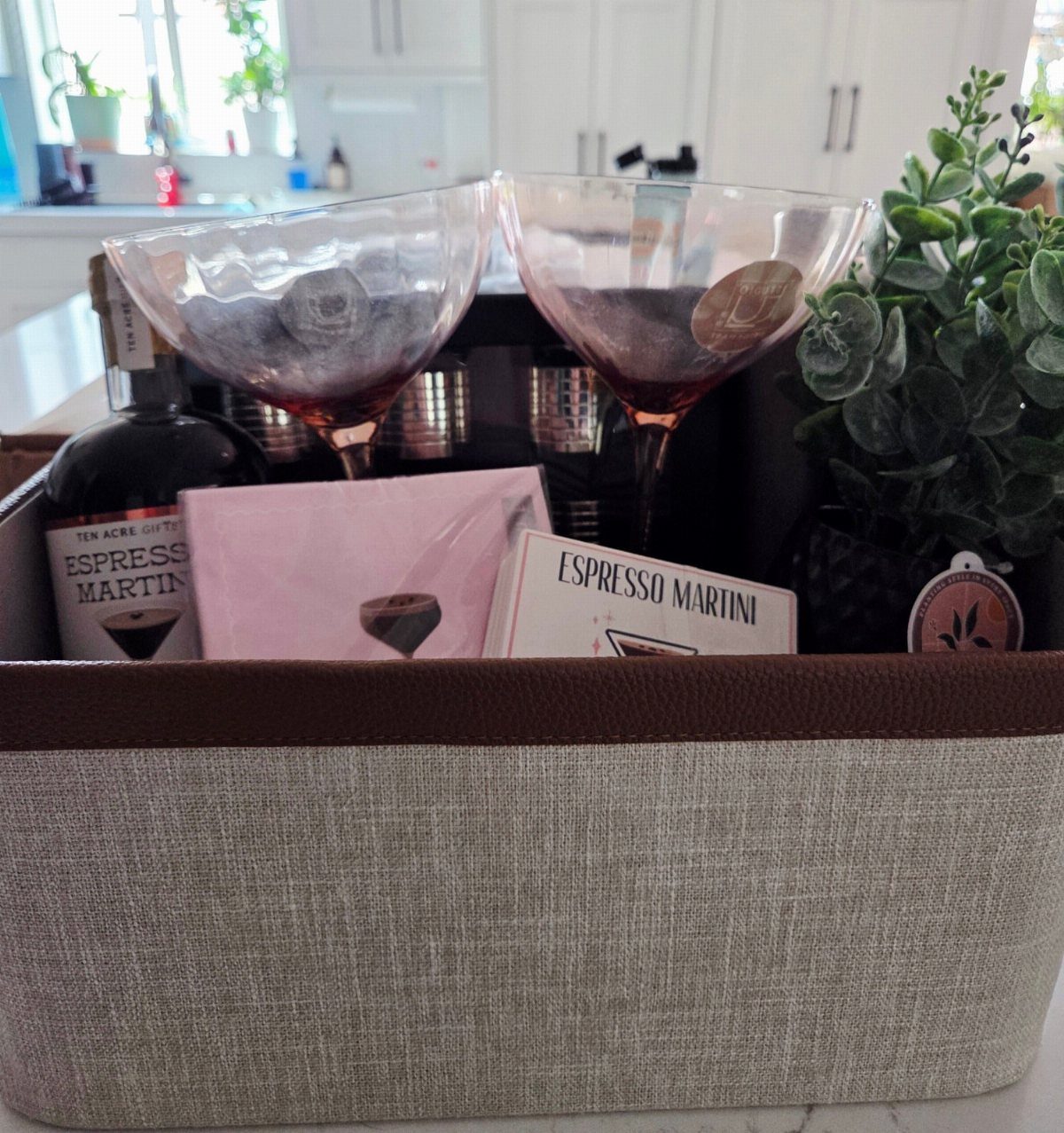Espresso martini gift basket with two glasses, liqueur bottle, and a small plant.