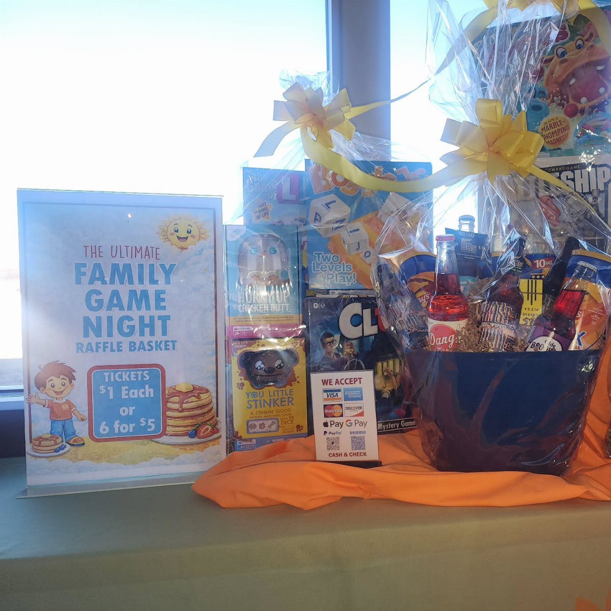 Blue gift basket filled with games and snacks for a family game night raffle.