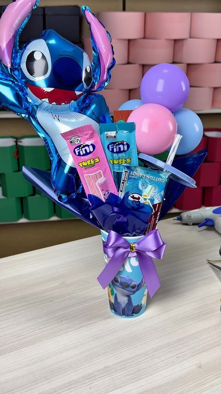 Stitch themed gift arrangement with blue foil balloon, candies, and purple bow.