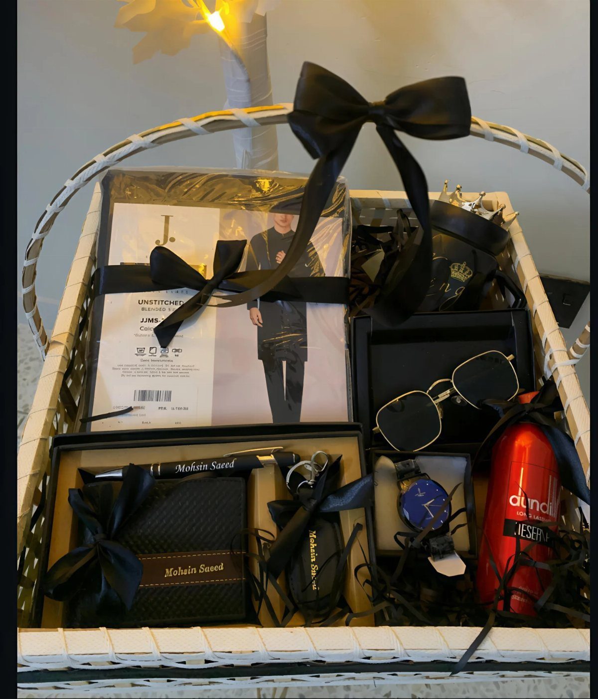 White wicker gift basket filled with men's accessories and a red thermos.
