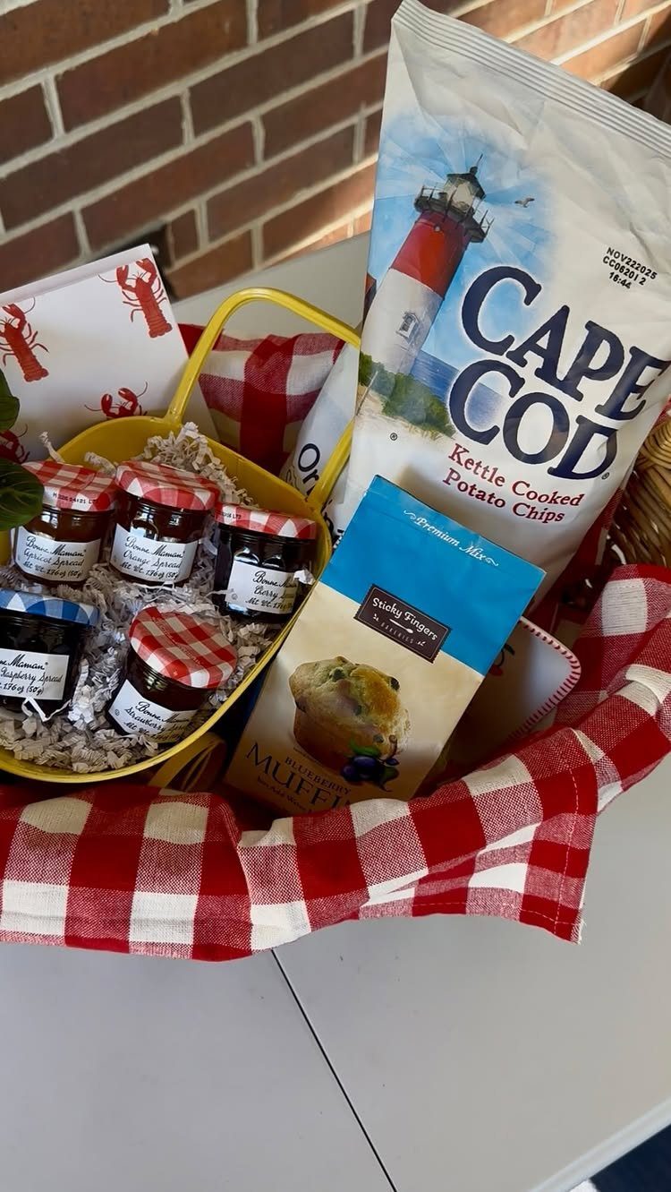 Yellow gift basket with potato chips, jam jars, and red checkered cloth.