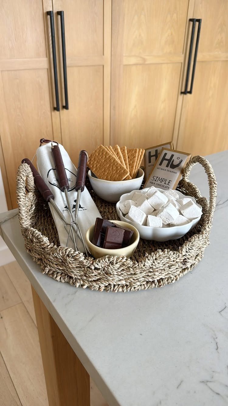 Woven basket filled with marshmallows, graham crackers, chocolate, and roasting sticks for s'mores.