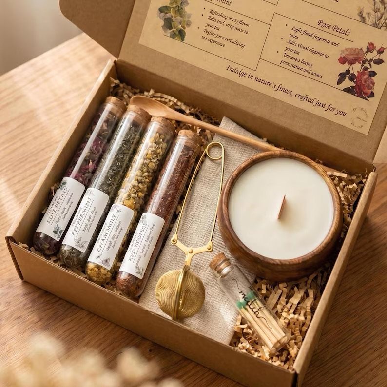 Tea gift set with loose leaf tea tubes, gold infuser, and scented candle.