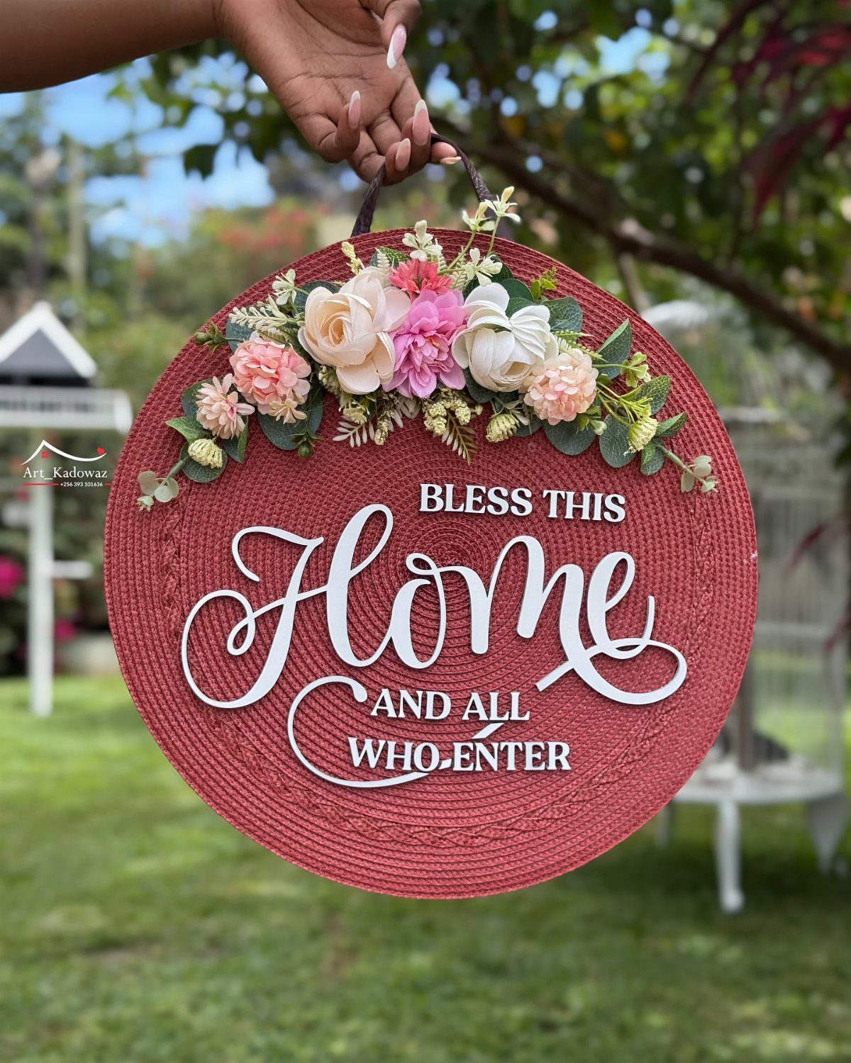 Circular red woven wall hanging with floral accents and a home blessing message.