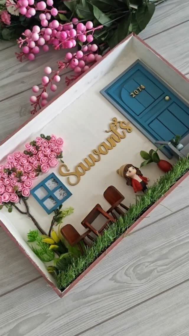 Miniature 3D diorama with a blue door, small figure, and pink roses.