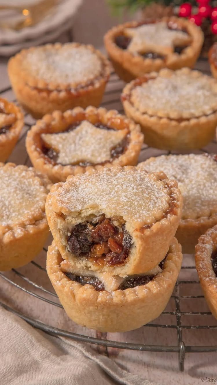 Mince pies with sugary crusts and fruit filling on a metal cooling rack.