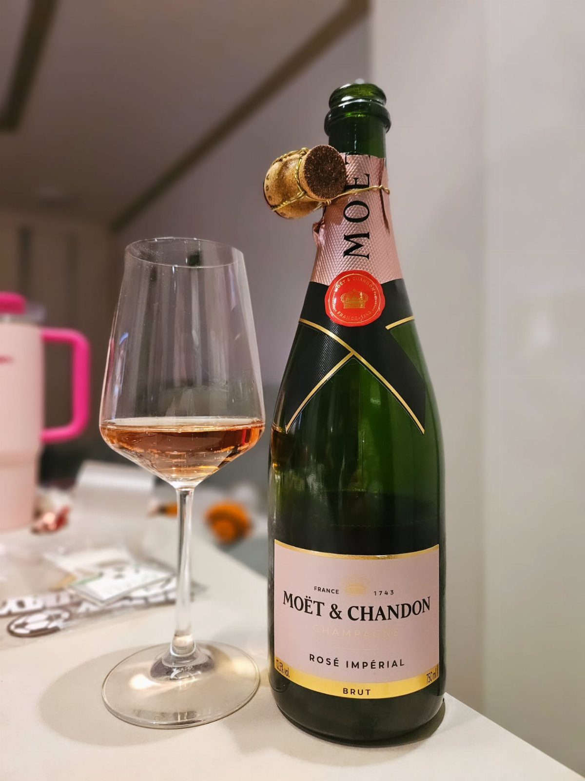Bottle of Moët & Chandon Rosé Impérial champagne and a glass of pink wine.