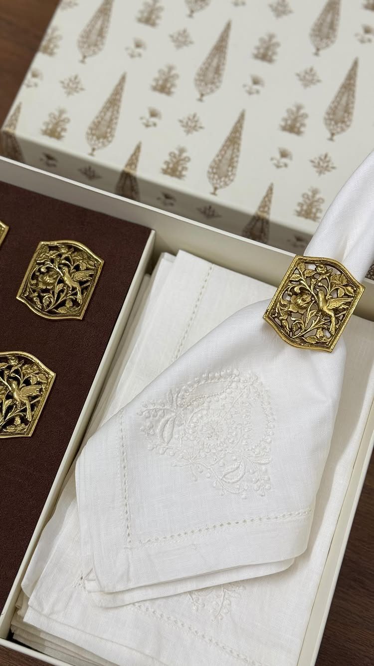 White embroidered cloth napkins with gold ornate napkin rings in a gift box