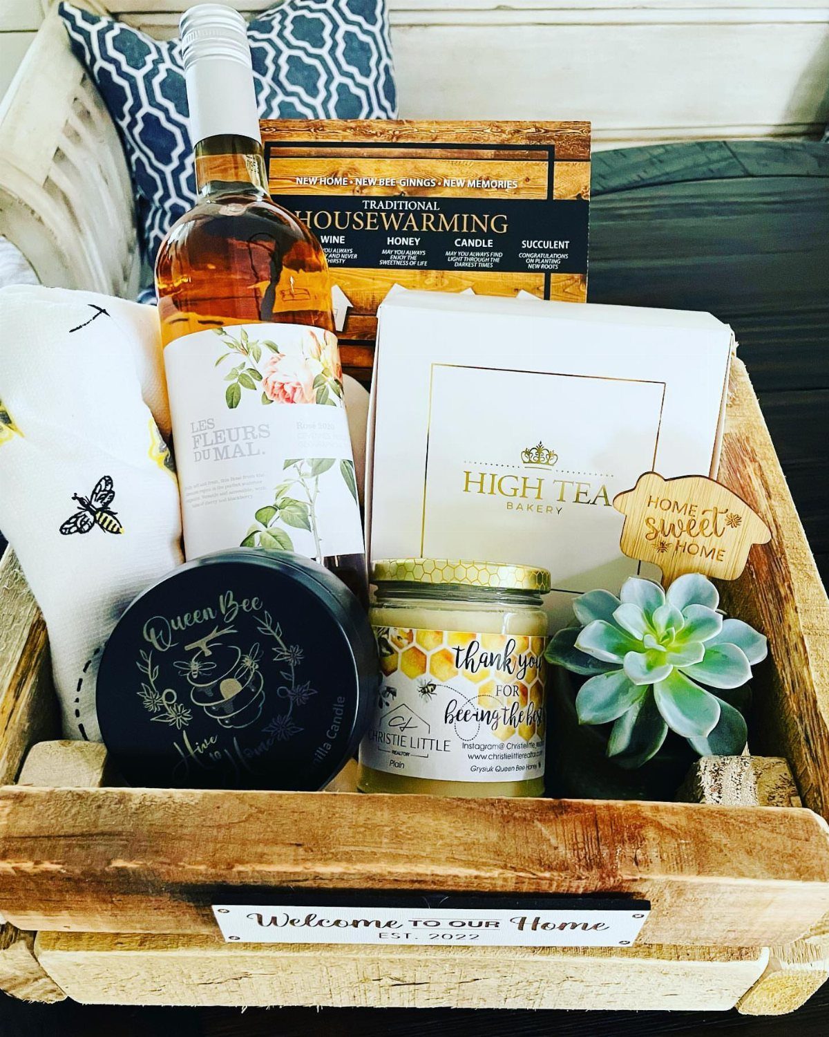 Wooden gift crate with honey, wine, a succulent, and bee-themed kitchen accessories.