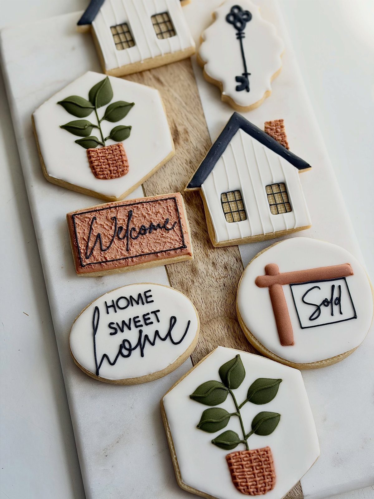 Iced sugar cookies in house and home shapes on a marble board.