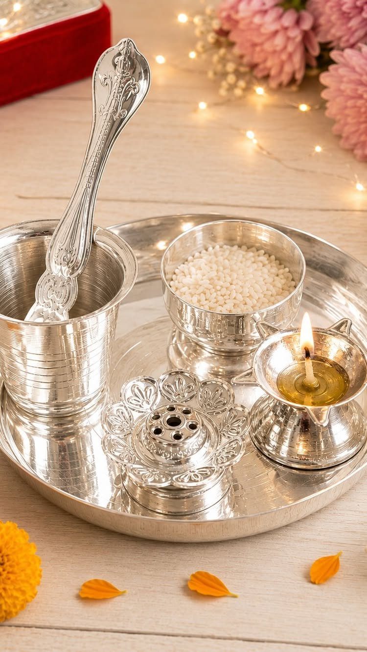 Silver puja thali set with rice, lit lamp, and incense holder on wood.