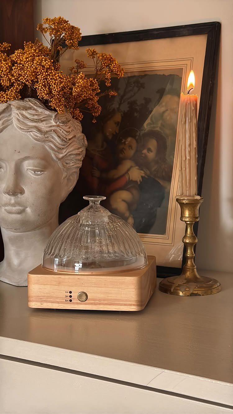 Glass dome on wooden base next to a classical bust and lit candle