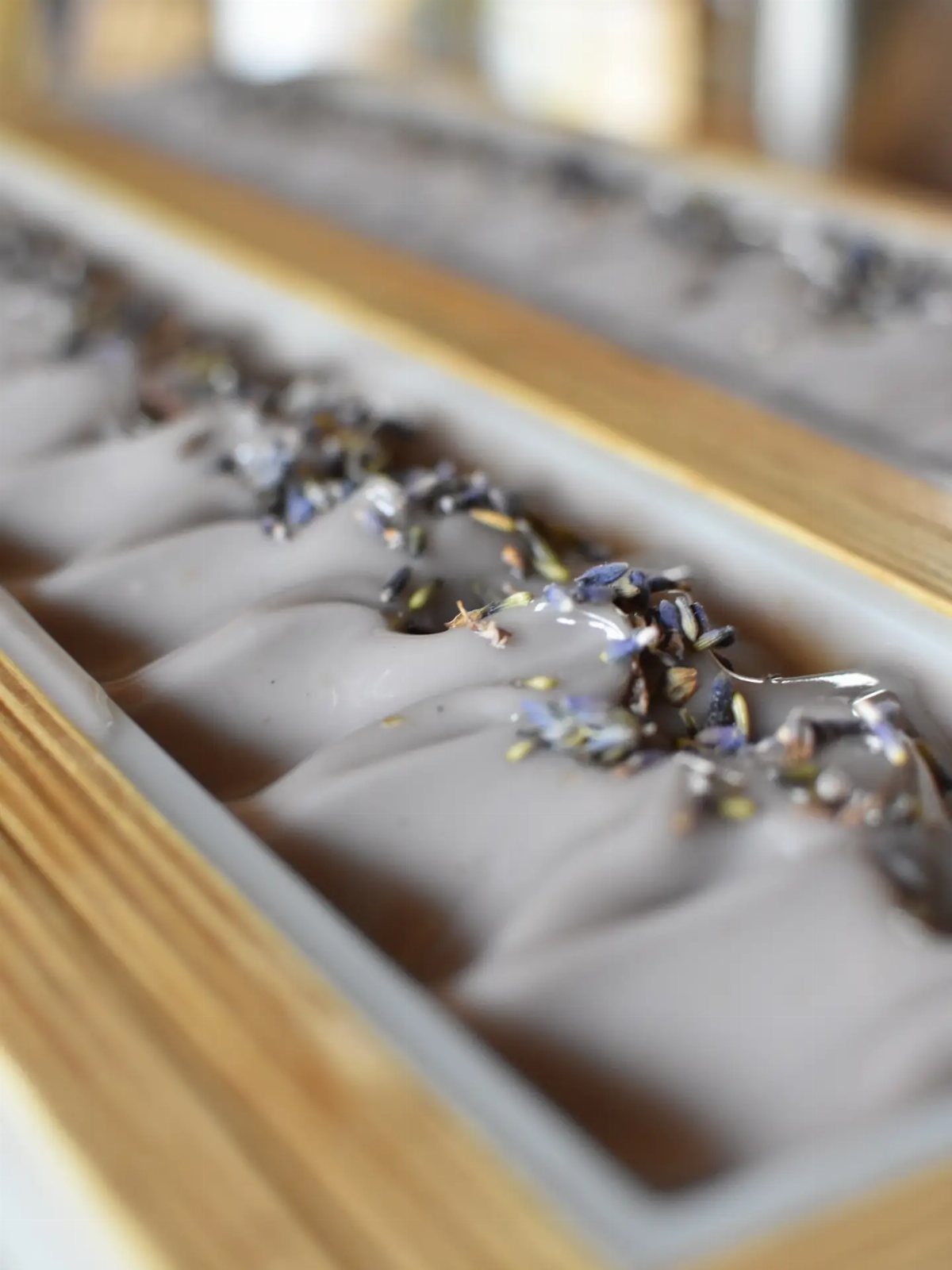 White wavy soap bar with dried lavender buds in a wooden tray