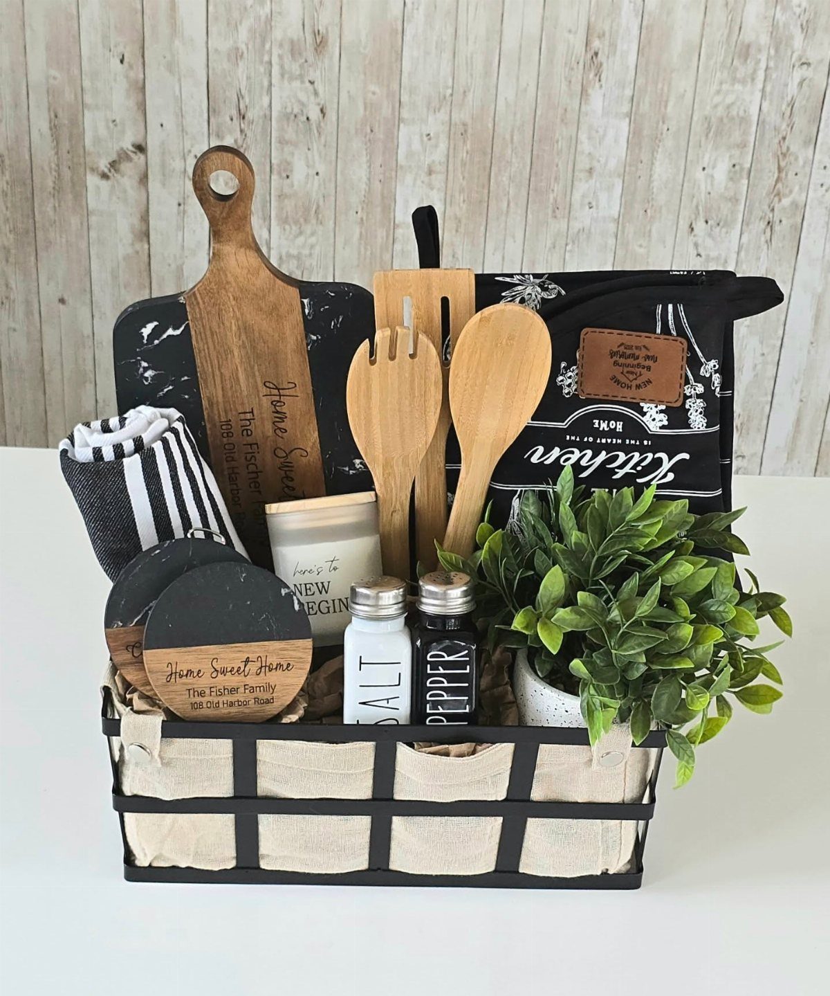 Housewarming gift basket with wooden kitchen tools, a small plant, and a candle.