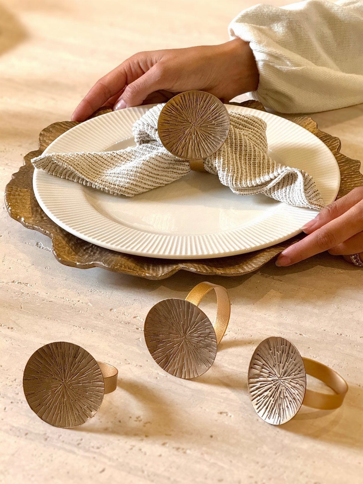 Beige striped napkins with gold circular rings on a white dinner plate