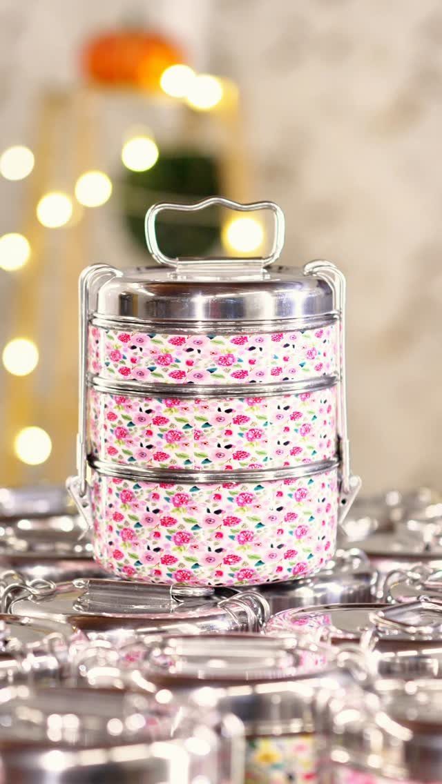 Stacked stainless steel tiffin lunch box with pink floral patterns and metal handle.