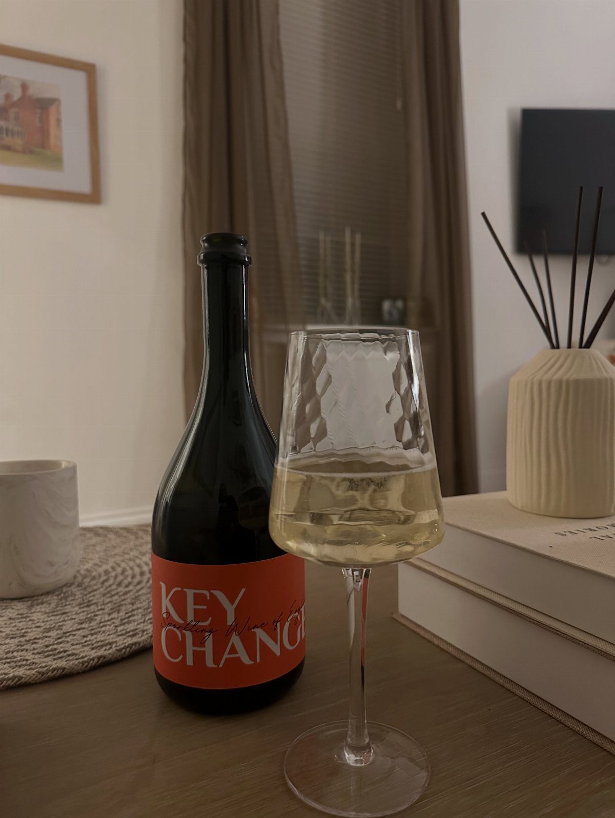 Bottle of white wine and a filled glass on a wooden table.