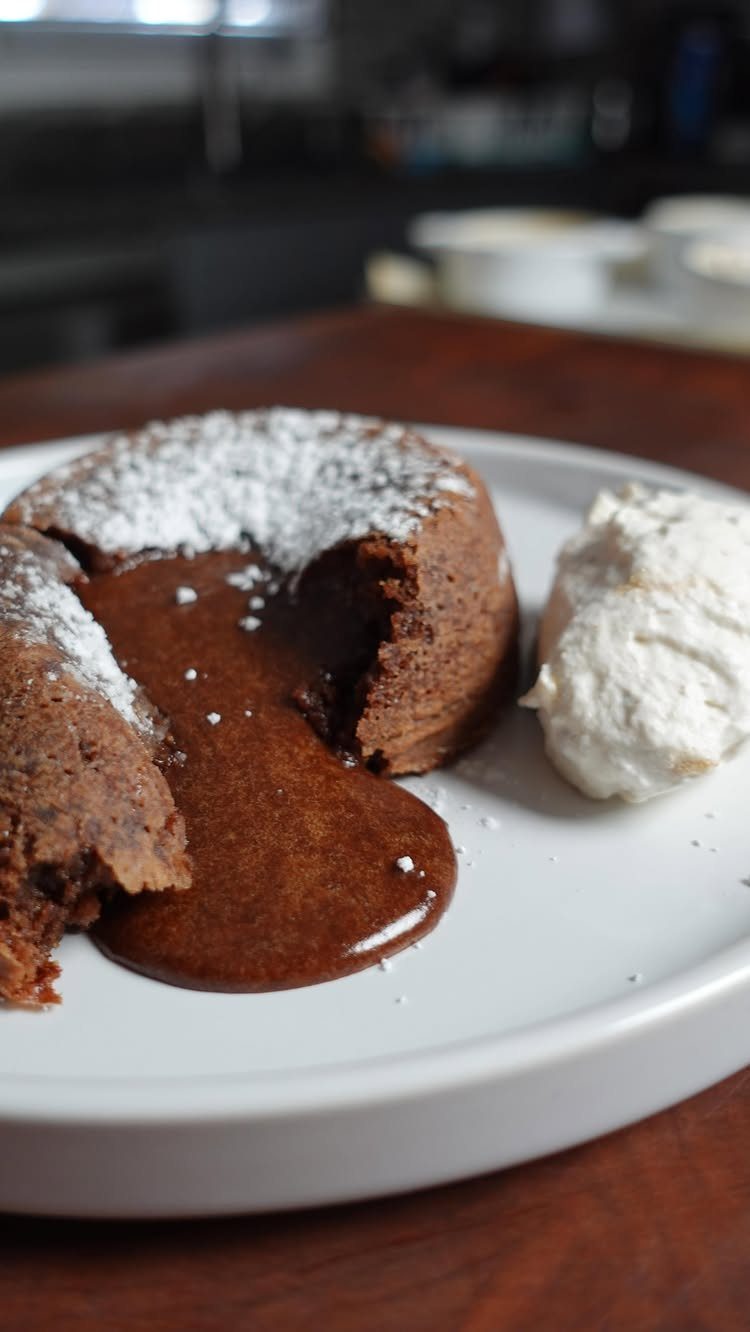 Chocolate molten lava cake with gooey center, powdered sugar, and whipped cream.