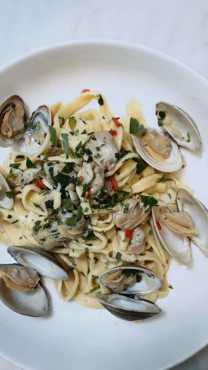 Linguine pasta with clams in a creamy sauce garnished with fresh parsley.