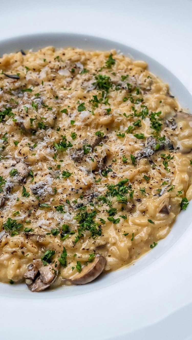 Creamy mushroom risotto in a white bowl topped with parmesan and fresh parsley.