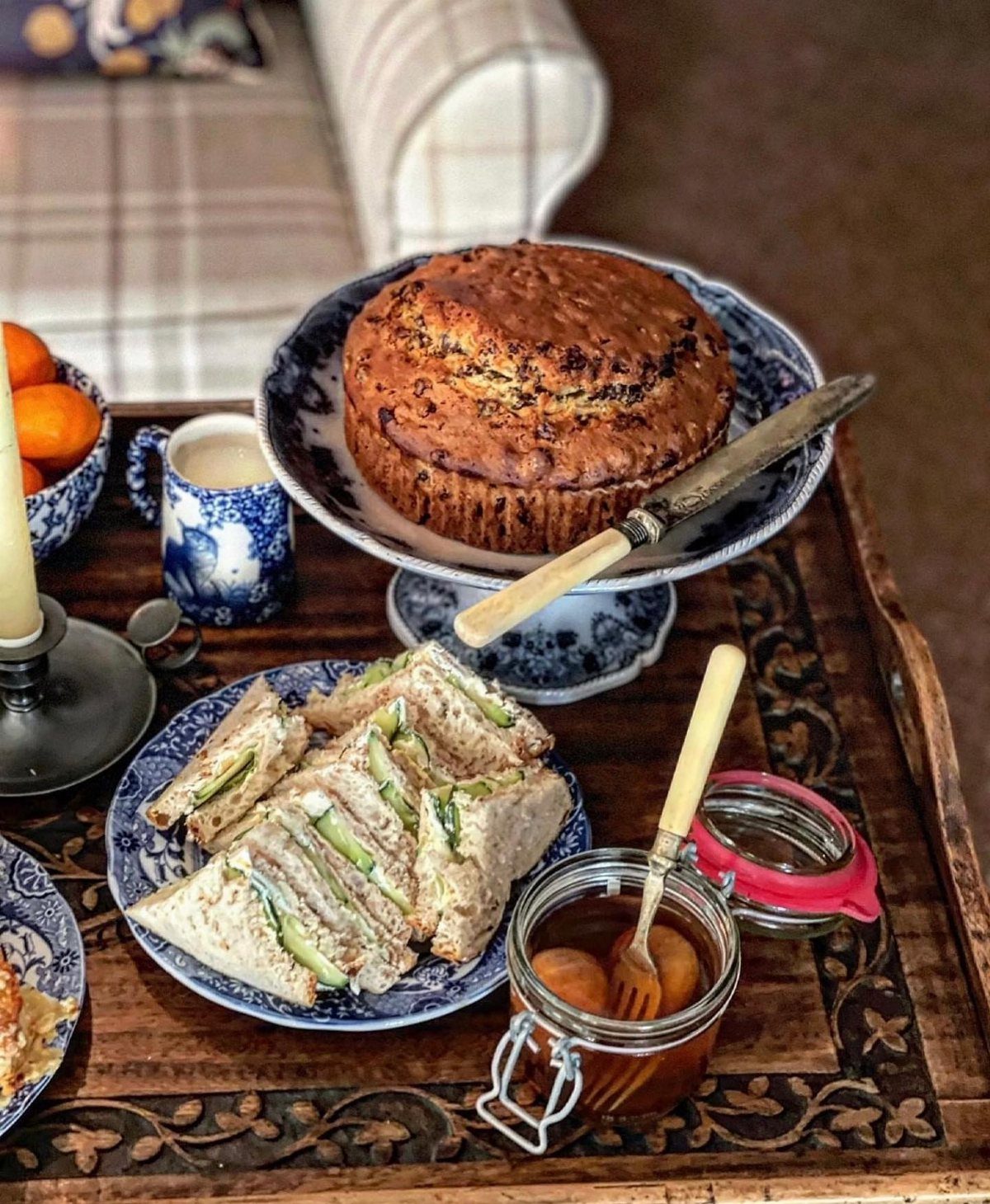 Cucumber tea sandwiches on a blue plate next to a cake and preserves.