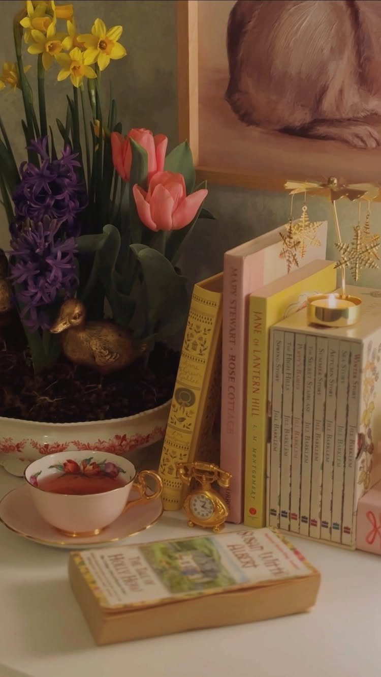 Vintage books, a teacup, and colorful spring flowers arranged on a white table.