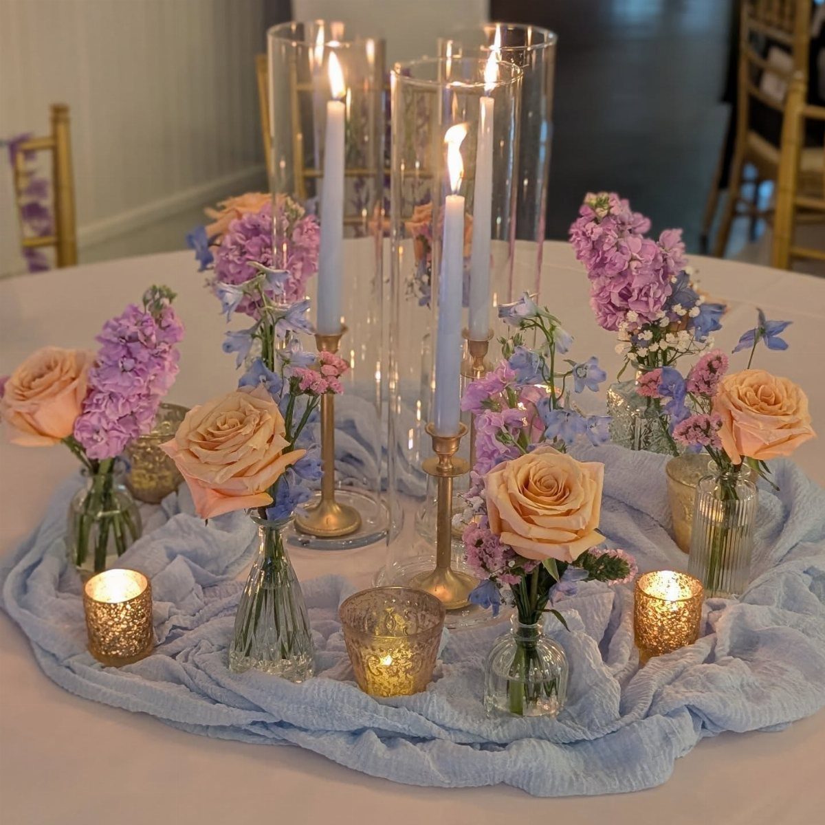 Wedding table centerpiece with taper candles, gold votive candles, and peach roses.